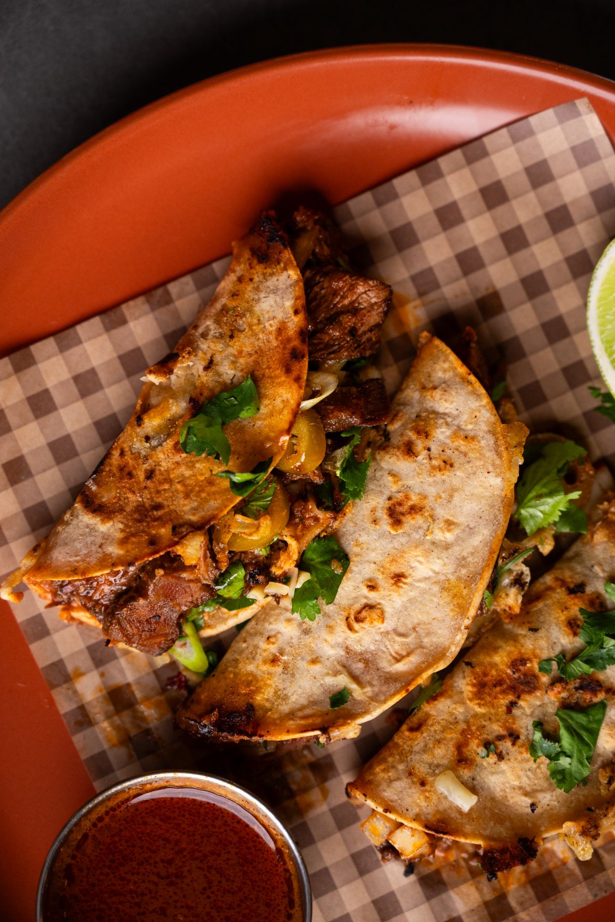 Close up of crispy birria tacos on gingham paper
