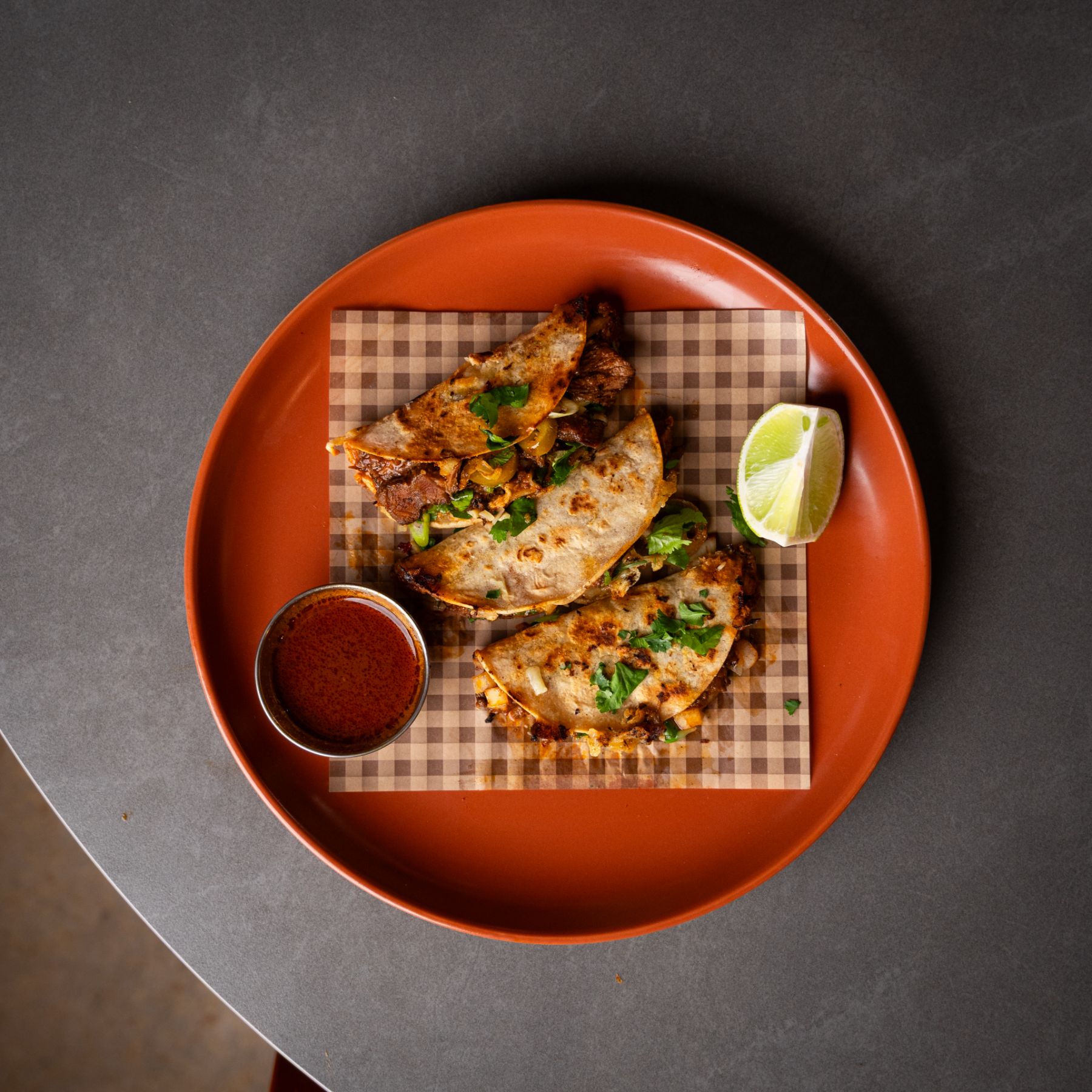 Birria tacos with consommé on a terracotta plate